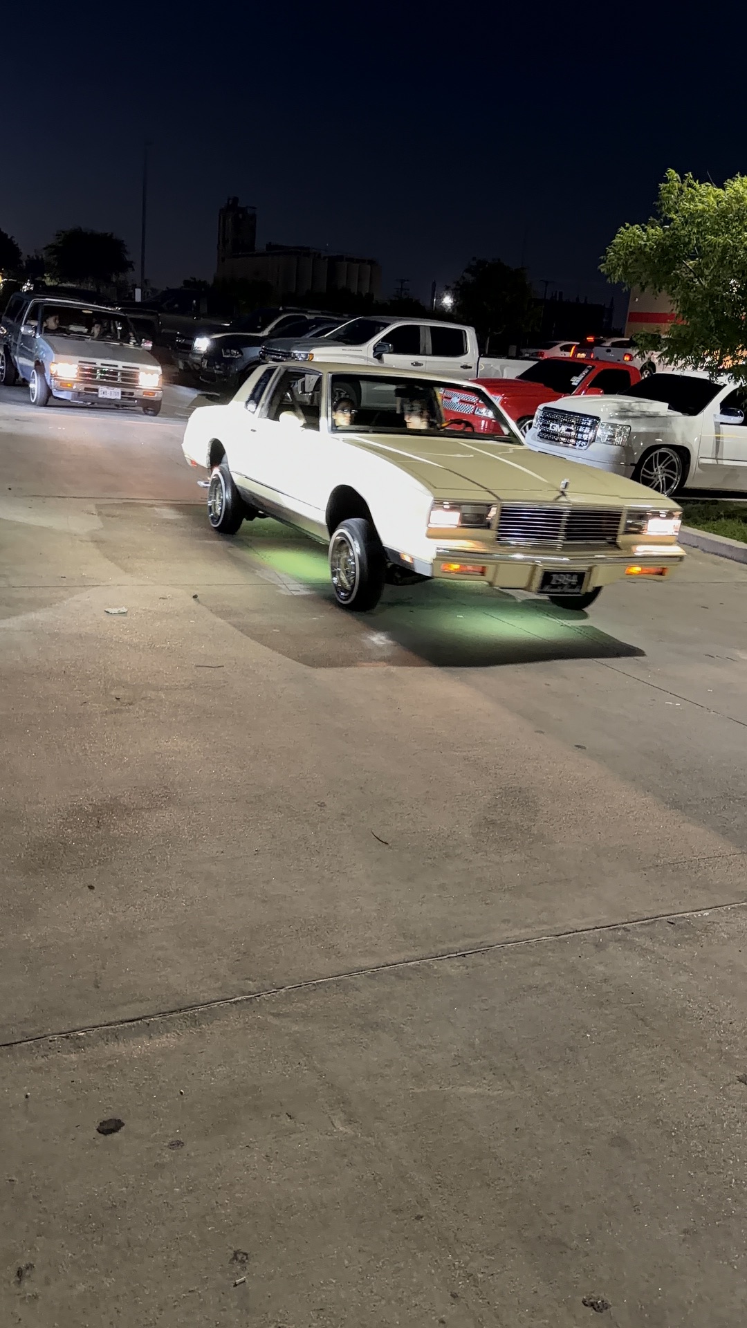 White Monte Carlo lowrider hopping on hydraulics with neon underglow