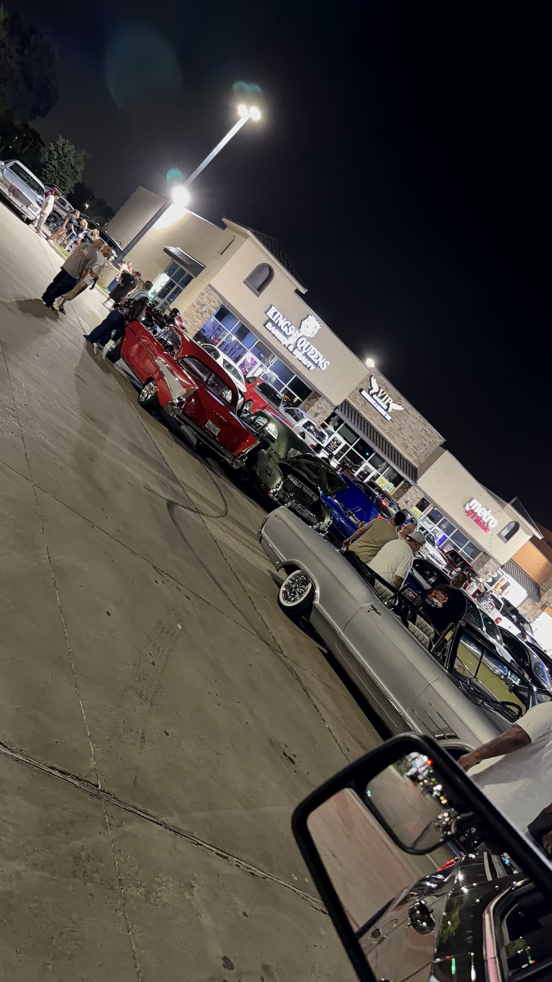 Night lineup of lowriders and cruisers gathered outside Kings & Queens